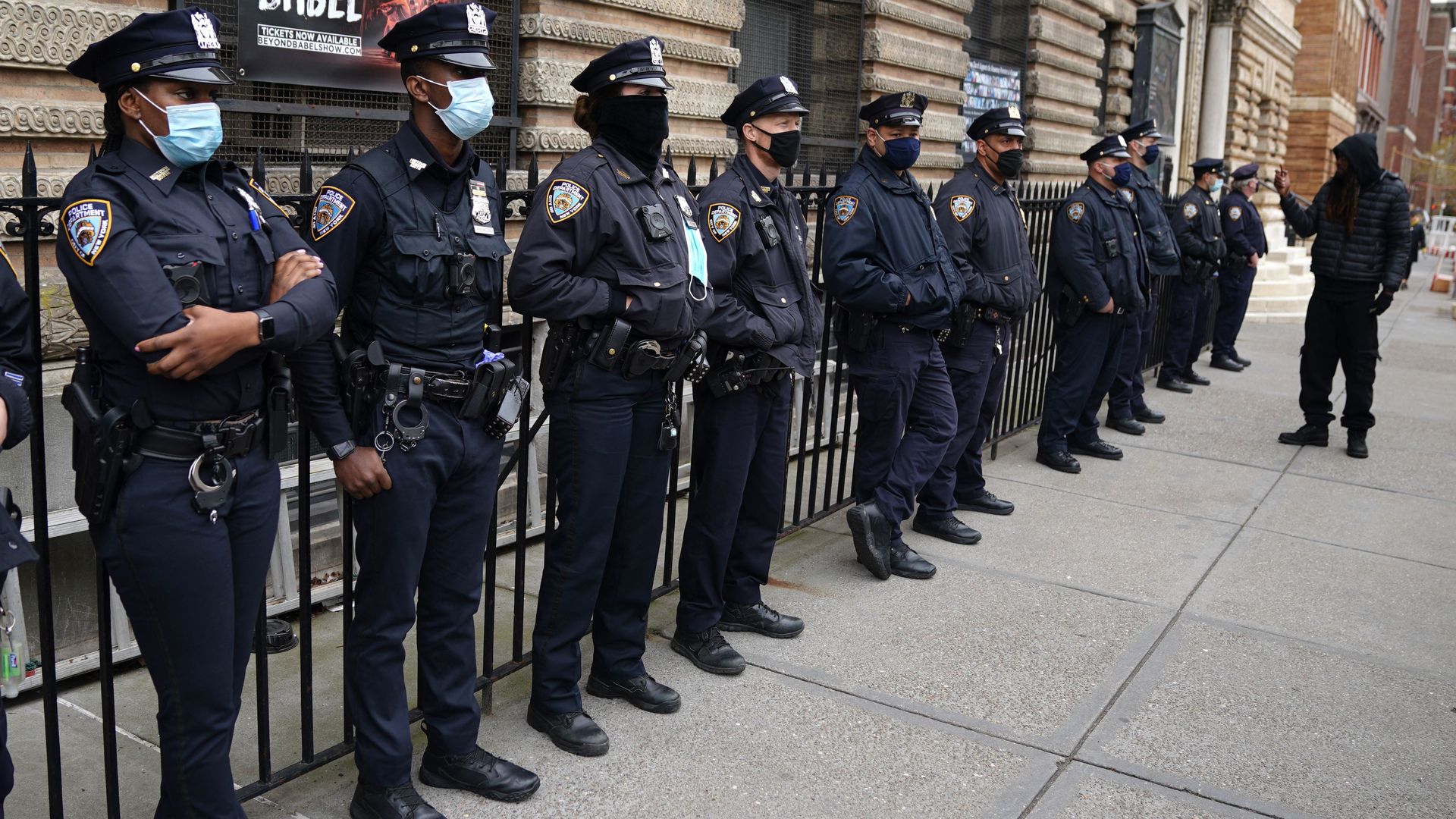 Police officers standing against a fence