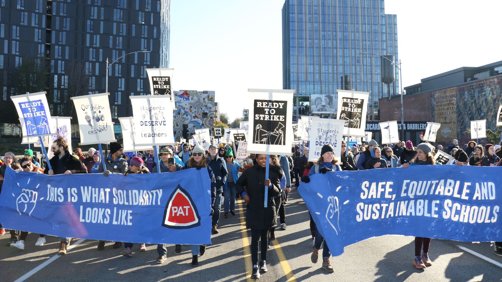 A photo of people walking down a street holding labor union signs.