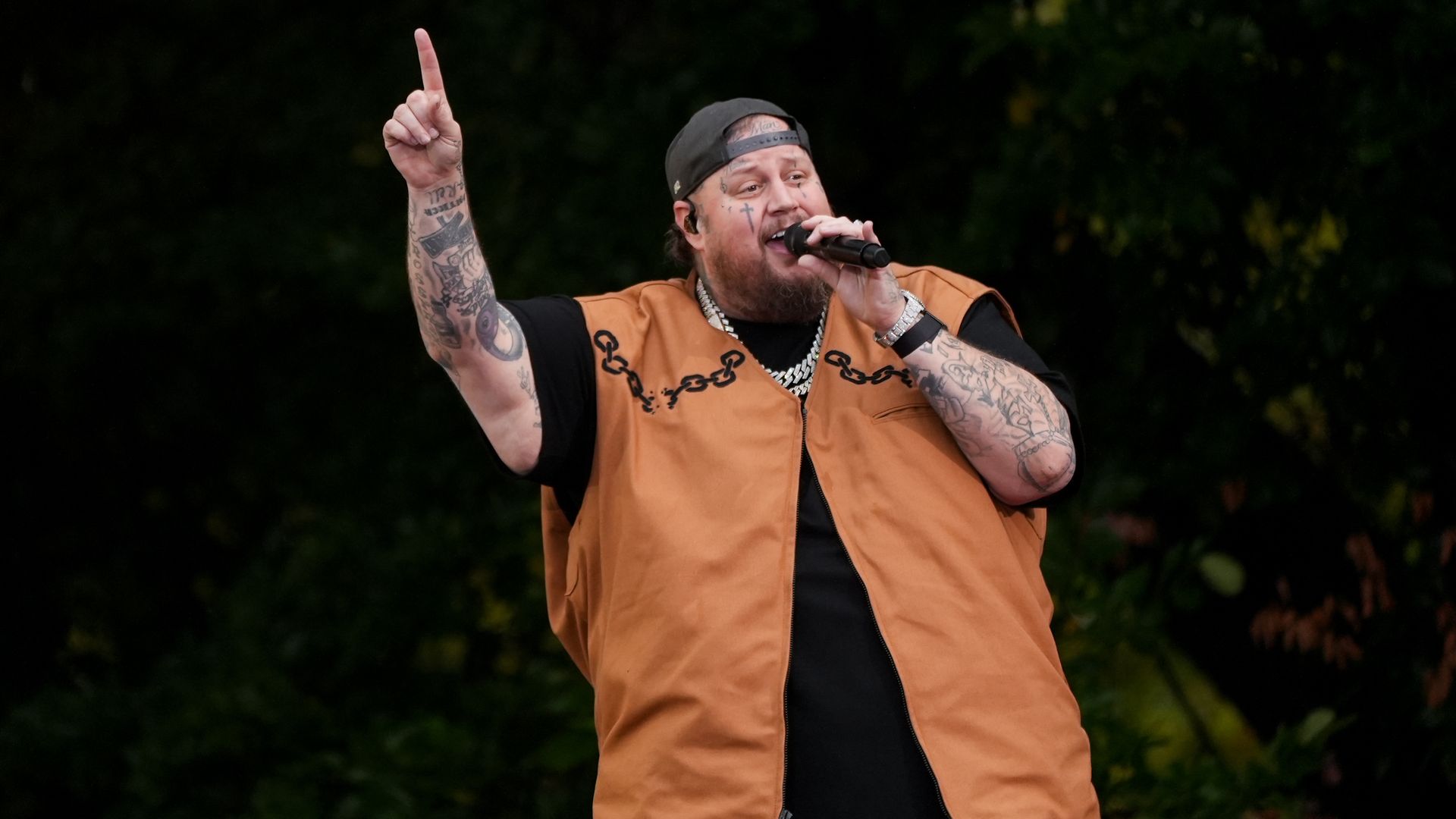 Singer Jelly Roll performs while pointing upwards. 