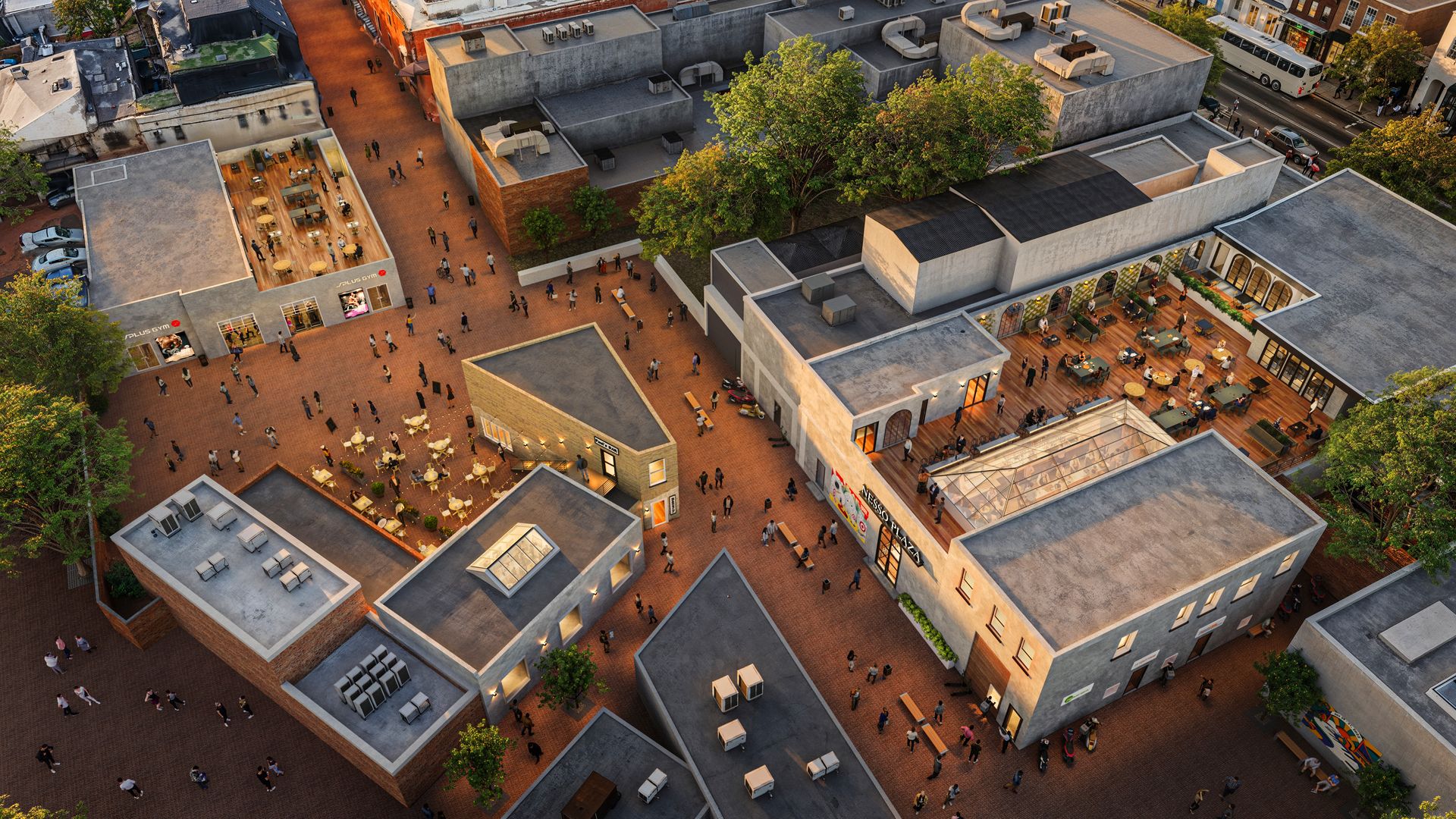 Aerial view of a lively urban plaza with brick walkways, outdoor seating areas, trees, and people walking and sitting around shops and cafes at sunset.