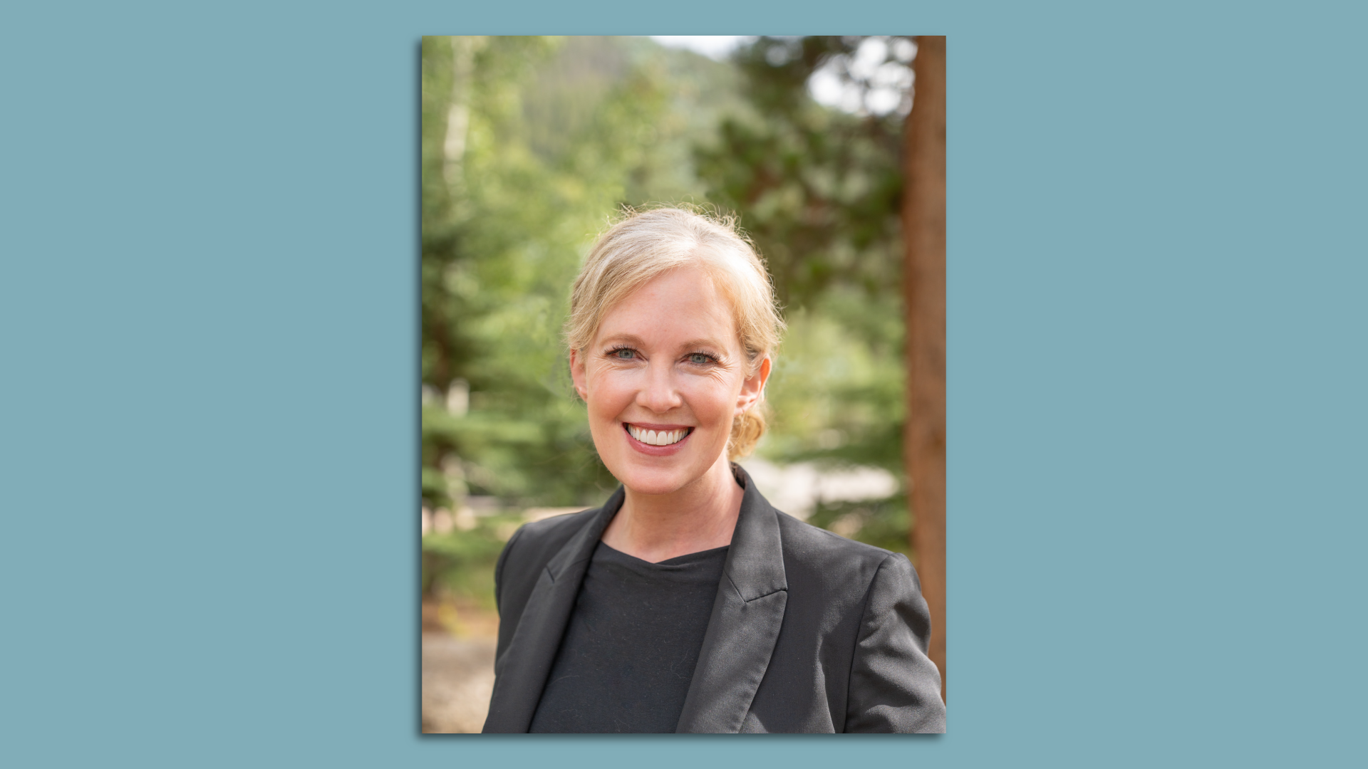 A white woman in a suit in front of trees