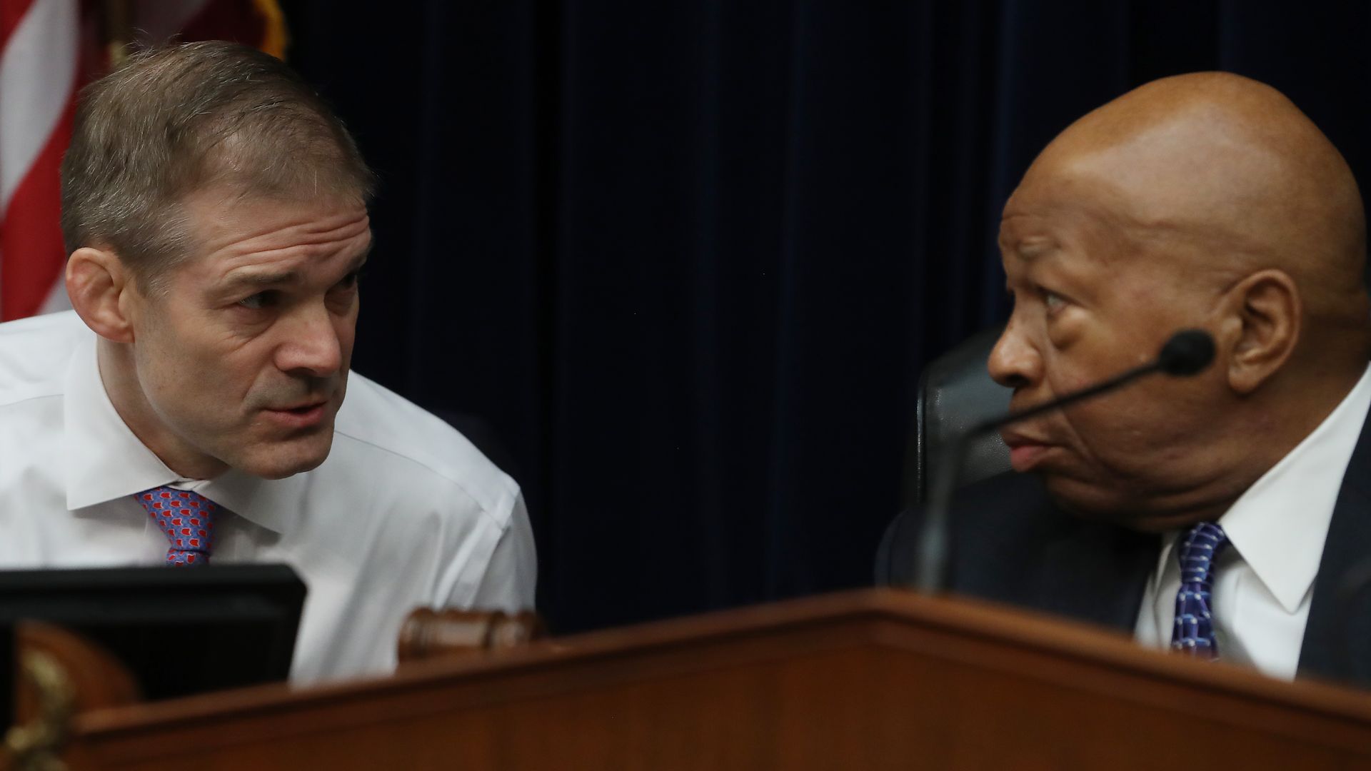 In this image, Jim Jordan (on the left) and Elijah Cummings (on the right) look at each other over the bench.