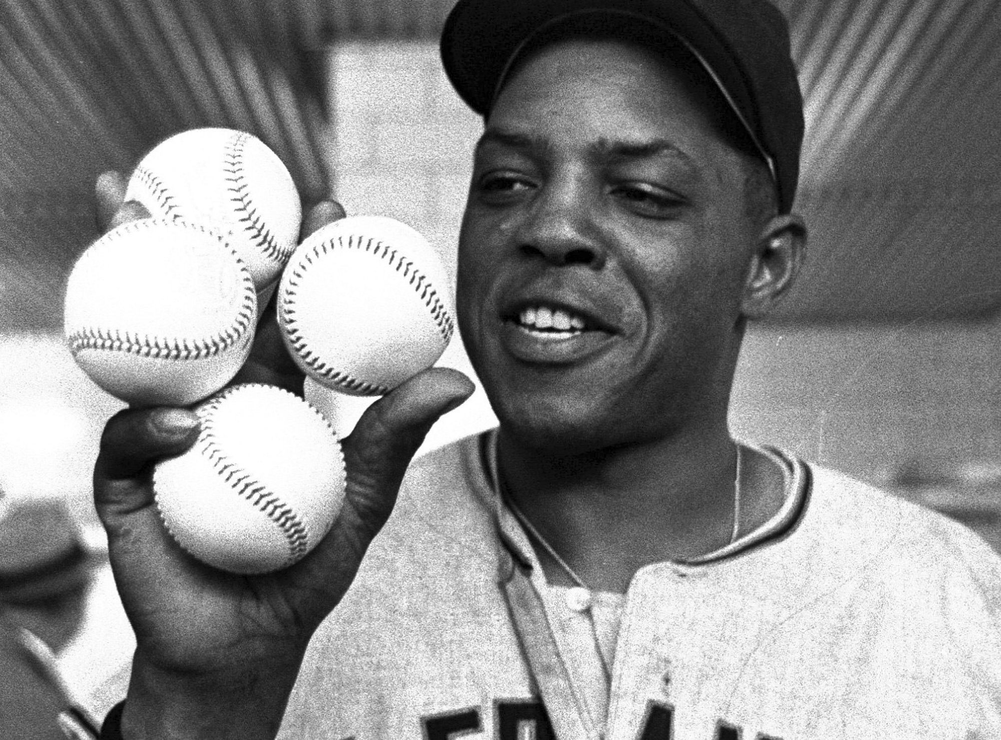 Willie Mays displays the four baseballs in the Giants clubhouse after hitting four homers during a game in 1961.