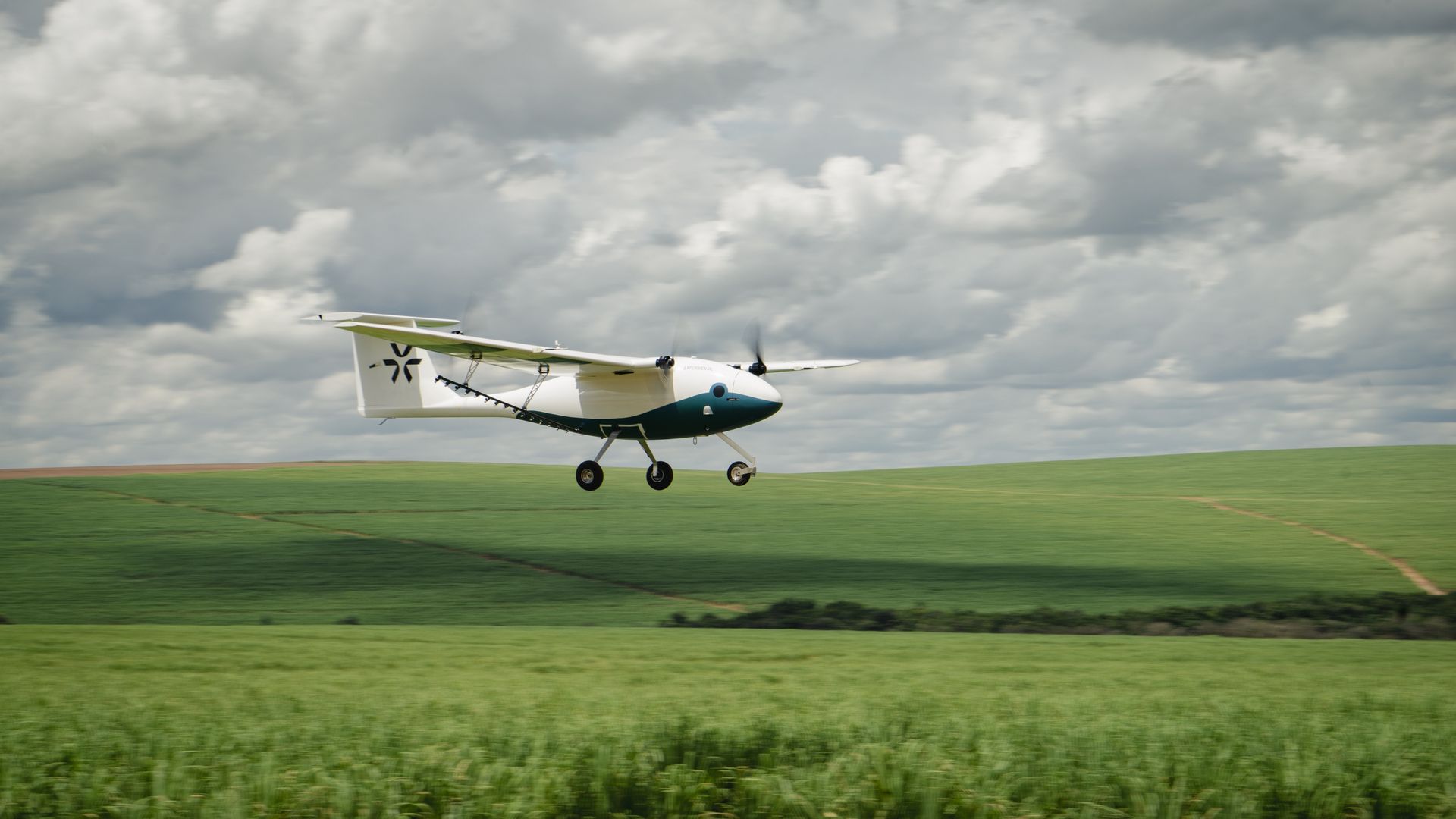 A Pyke pilotless airplane flies low above green cropland.