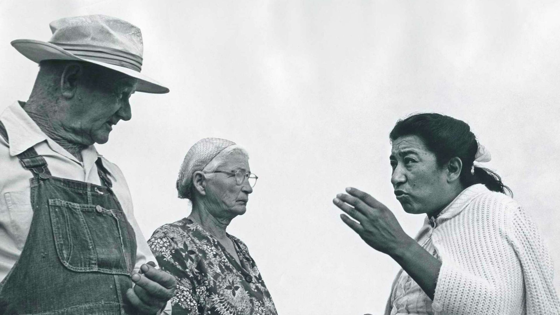 In this black and white photo, Maria Moreno speaks to two people with her hand out